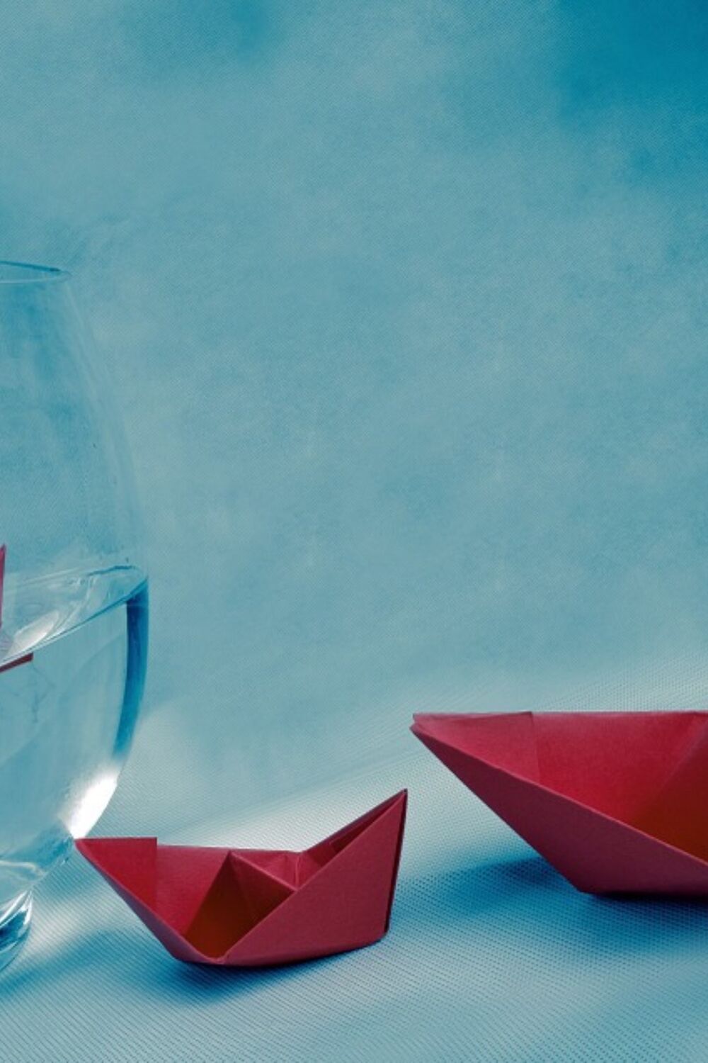 Two red paper boats beside a glass of water